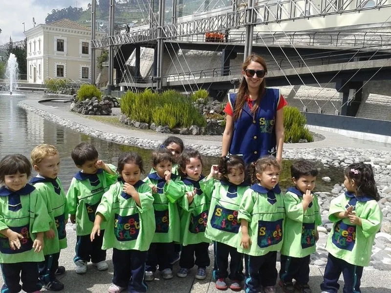 Andrea Erazo en su uniforme de profesora de nivel incial con un grupo de niños