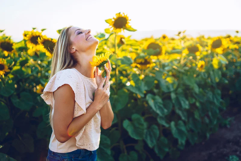 Mujer rubia feliz y riendo en un campo de girasoles